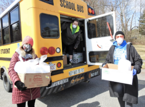 Volunteers loading supplies into yellow school bus