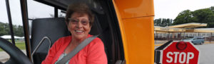 Ginger Caggiano sits in the driver seat on a school bus.